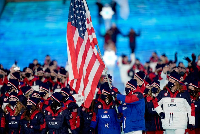 Brittany Bowe and John Shuster, of the United States, leads their team in during the opening ceremony of the 2022 Winter Olympics.