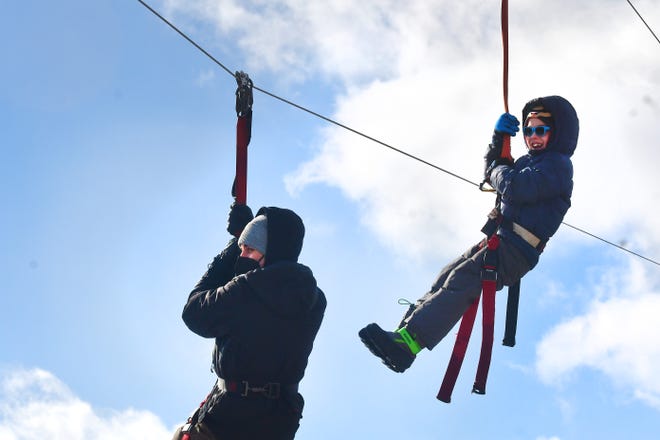Chris Fix (left) with his son Jason wear a harness as they zoom down a zip line during Winter Blast in Royal Oak on Saturday, February 19, 2021.