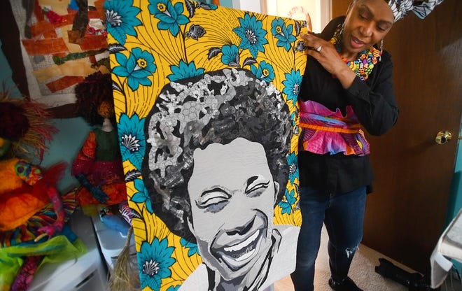 Artist April Anue Shipp holds up an art piece of her son Lance.