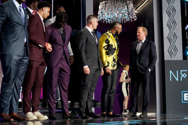 NFL Commissioner Roger Goodell, right, talks to Florida State defensive end Jermaine Johnson II, in yellow, during the first round of the NFL football draft Thursday.