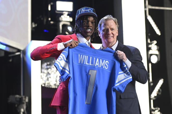 Jameson Williams poses with NFL Commissioner Roger Goodell onstage after being selected 12th by the Detroit Lions during round one of the 2022 NFL Draft.
