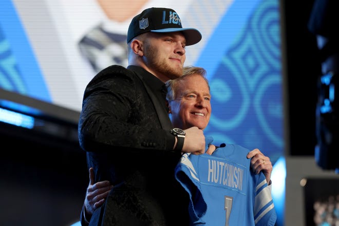 From left, Michigan defensive end Aidan Hutchinson, and NFL Commissioner Roger Goodell hold up the jersey for the Detroit Lions 2nd pick in the NFL football draft.