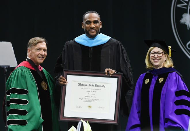 NBA and MSU basketball star Steve Smith, center, receives a honorary degree from Michigan State University President Samuel Stanley Jr., M.D. and Michigan State University Provost and Executive Vice President for Academic Affairs Teresa Woodruff, Ph.D. during the MSU commencement ceremony at the Breslin Center.