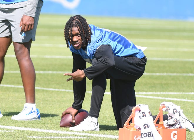 Lions rookie wide receiver Jameson Williams, who did not participate in drills, flashes two fingers while on the sidelines.