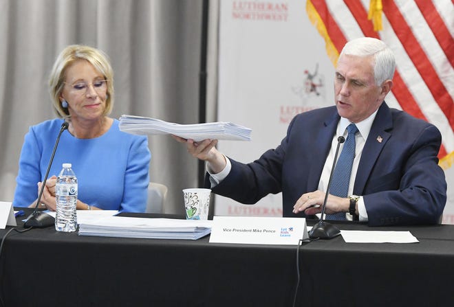 Former Education Secretary Betsy DeVos and former Vice President Mike Pence show a pile of signed petitions for the " Student Opportunity Scholarship " during a discussion at Lutheran High School Northwest about a school of choice tax credit initiative in Rochester Hills, Michigan, on May 17, 2022.