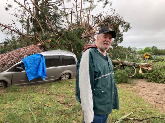 Jack Elliott stands beside his van that was struck by a tree during a tornado in Gaylord, Mich., Friday, May 20, 2022. Elliott was inside his house during the storm and was uninjured.