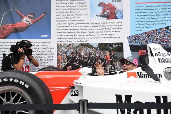 IndyCar driver Helio Castroneves has no trouble fitting into his 2000 winning car at the Grand Prix legacy tent in the Fan Zone.