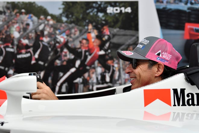 IndyCar driver Helio Castroneves has no trouble fitting into his 2000 winning car at the Grand Prix legacy tent in the Fan Zone.