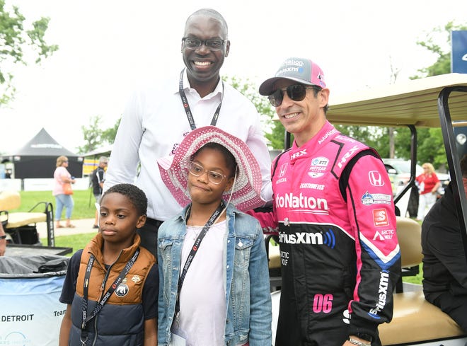 IndyCar driver Helio Castroneves, right, poses with Lt. Gov. Garlin Gilchrist II and two of his children, Garlin III, left, and Emily, both 8, at the Chevrolet Detroit Grand Prix on Belle Isle in Detroit on June 5, 2022.   
(Robin Buckson / The Detroit News)