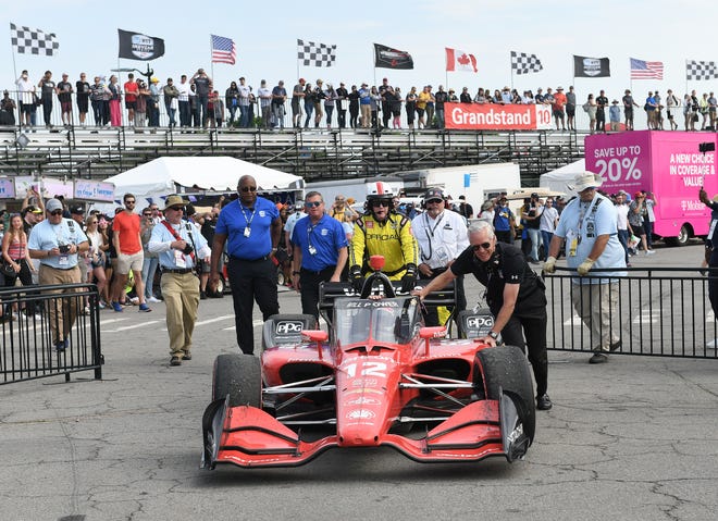 Officials push the #12 car towards the winner's circle with winner Will Power in it  at the Detroit Grand Prix.
