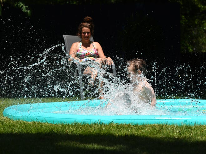 Shepherd Harrington, 4, jumps into his splash pad at his home on Lewiston St. in Ferndale, as his mother Camryn Harrington, 33, looks on.