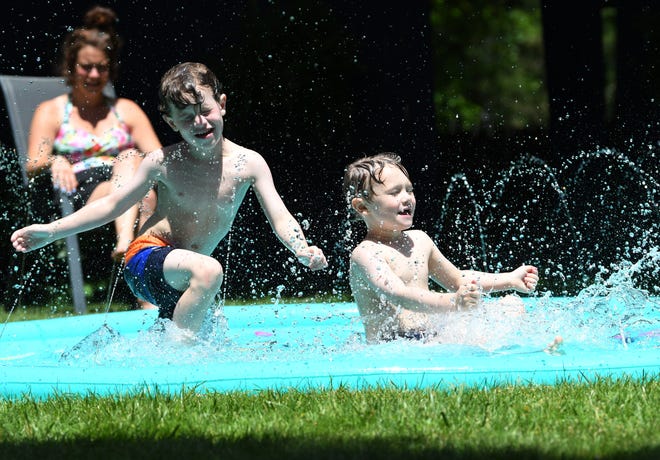 l-r, Cash Harrington, 6, and his brother Shepherd Harrington, 4, plays in their splash pad at their home on Lewiston St. in Ferndale, as his mother Camryn Harrington, 33, looks on.