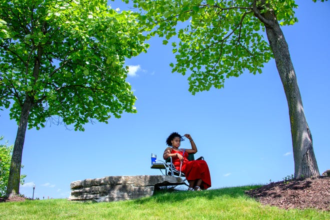 Anne Linder, Detroit, relaxes as she smokes a hookah in the shade of the trees at the Detroit Riverwalk near Atwater and Rivard Streets, Wednesday, June 15, 2022.