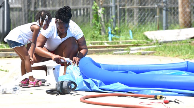 Sheena Owens and her daughter, Cali Davis, 4, both of Highland Park, put together a swimming pool in the back yard during 95-degree-plus temperatures, Wednesday afternoon, June 15, 2022.