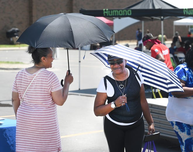 Melanie Staten (left) and Lisa Hunt of Detroit use umbrellas for shade from the sun outside the Adams Butzel Recreational Complex during Senior Fun Day in Detroit on Wednesday, June 15, 2022.