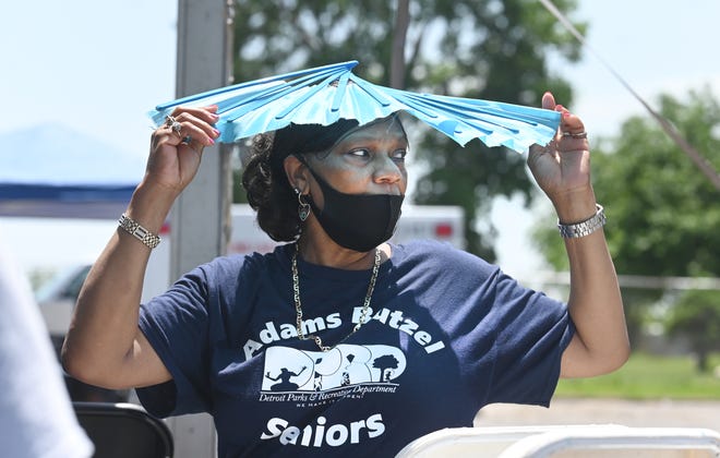 Garcia Davis of Detroit uses a folding fan over her head to block the sun outside the Adams-Butzel complex in Detroit on Wednesday, June 15, 2022.