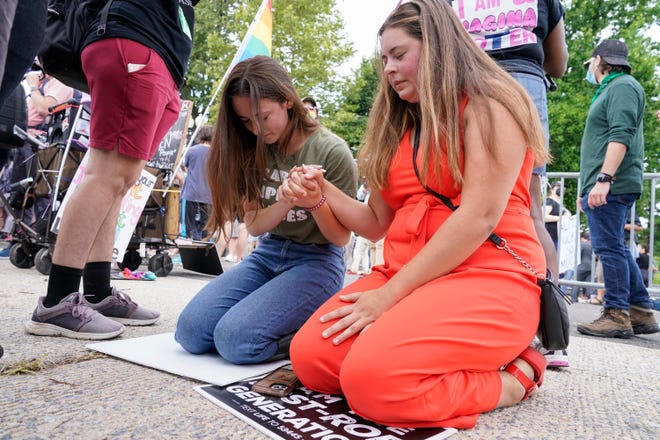 Anti-abortion activists Maggie Donica, 21, right, and Grace Rykaczewski, 21, left, pray following the Supreme Court's decision to overturn Roe v. Wade, federally protected right to abortion, in Washington, Friday, June 24, 2022.