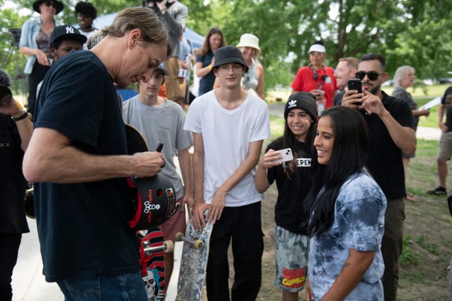Legendary skateboarder Tony Hawk autographs a helmet for Sofia Claudino, 13, of Shelby Township and her mother Paula Chestert, right, during the grand opening of the new Chandler Park Skatepark in Detroit.