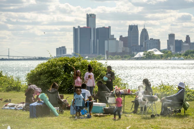 Families cook food and hang out before the start of the annual fireworks show, on Belle Isle, in Detroit, June 27, 2022.