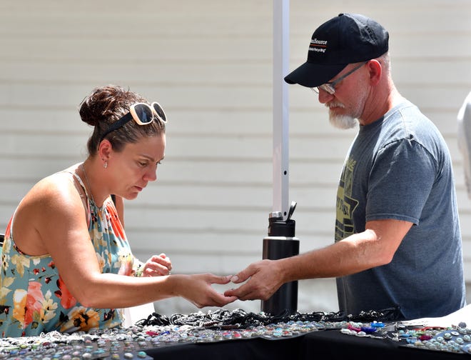 Melanie Bowyer shows her husband, Dan, both of Flint, a ginger snap charm (that attaches to a bracelet) at the Great Lakes Treasures booth, out of Kalamazoo, Saturday afternoon, July 2, 2022. Melanie says, "I have more than one hundred. I’m addicted to them."