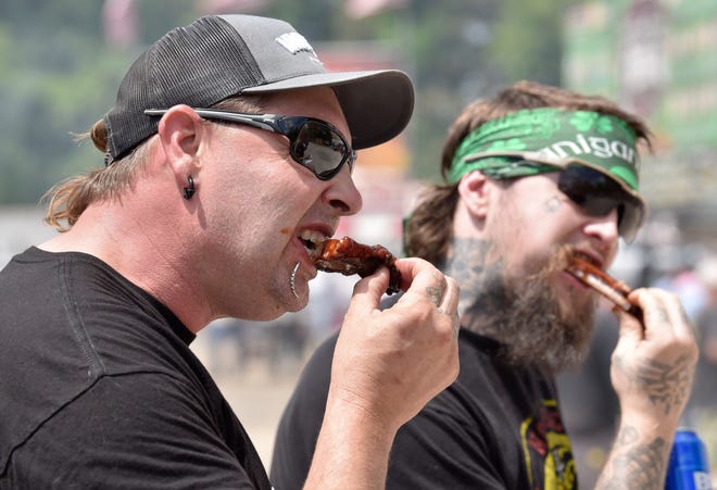 Richard Bowlby, left, a.k.a. freak show performer "Rampage Asylum," and friend Kevin Masten, both of Davisburg, eat ribs from Cowboys Barbeque & Rib Co., Saturday afternoon, July 2, 2022. Cowboys is out of Fort Worth, Texas.
