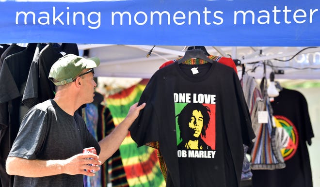 Keith Bardol, of Clinton Twp., checks out a Bob Marley T-shirt at the ABS Clothing and More merchandise booth, which is out of Grand Rapids, Saturday afternoon, July 2, 2022.