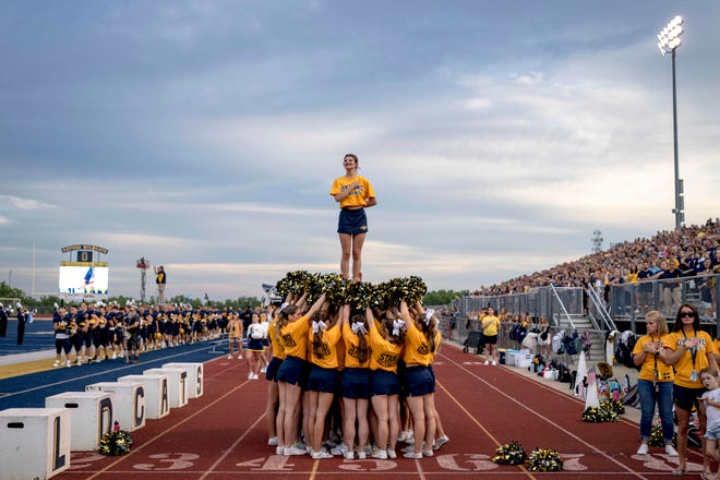 Senior cheerleader Lexi Acton, 17, is held in the air during the national anthem of the high school football game between the Oxford Wildcats and Birmingham Groves Falcons at Oxford High School in Oxford, Mich. on Sept. 2, 2022.