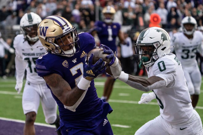 Washington wide receiever Ja'Lynn Polk, front left, catches a touchdown pass against Michigan State defensive back Charles Brantley, right, during the first half of an NCAA college football game, Saturday, Sept. 17, 2022, in Seattle.