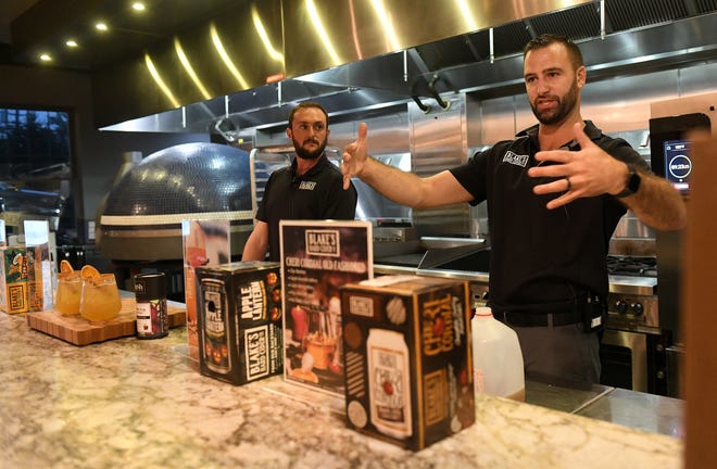 Kevin DeVries, right, of Blake's Hard Cider Co. talks about the toasted lantern drink that is made with a reduced hard cider and spices at Dish and Design Cozy Comfort event at  Great Lakes Culinary Center in Southfield, Mich. on Sept. 20, 2022.