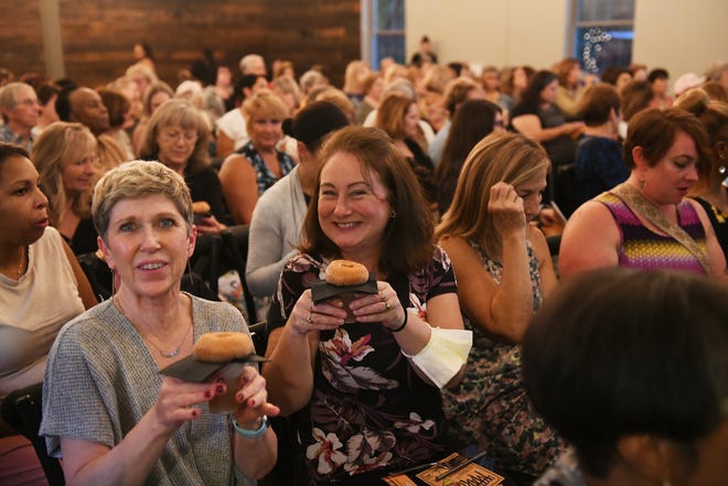 From left, Lynn Dirnberger of Sterling Heights and Kelly Greenwald of Wixom about to try the doughnuts from Blake's Hard Cider Co. at Dish and Design Cozy Comfort event at  Great Lakes Culinary Center in Southfield, Mich. on Sept. 20, 2022.
