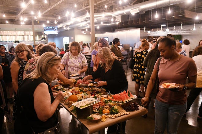 Angela Amour, 38, of Detroit, right, and others partake in the appetizers provided by Busch's Fresh Food Market at Dish and Design Cozy Comfort event at  Great Lakes Culinary Center in Southfield, Mich. on Sept. 20, 2022.