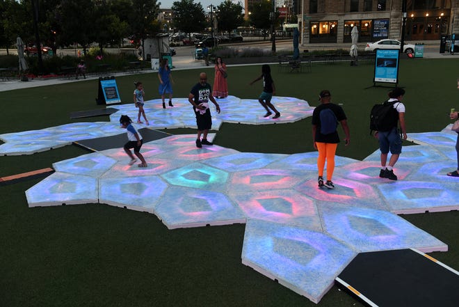 As dusk falls, the colors become more visible as people play, run and jump on The Last Ocean art installation at Beacon Park.