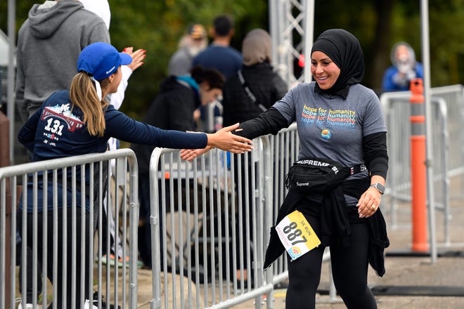 Sandy Charara of Canton, right, is congratulated by well wishers as she crosses the finish line of a 5K run hosted by Zaman International at Ford Field Park, Saturday, Sept. 24, 2022, in Dearborn, Mich. (Jose Juarez/Special to Detroit News)