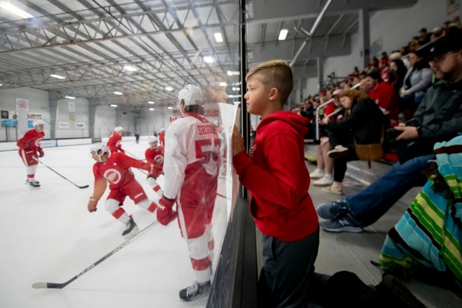 Nine-year-old Joey Manzella, of Armada, tries to get the attention of the players during the Red Wings’ training camp at Centre Ice Arena.