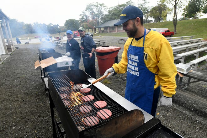 Volunteer Tarik Turfe helps grill hamburgers at the Zaman International 13th annual Run Walk Picnic at Ford Field Park, Saturday, Sept. 24, 2022, in Dearborn, Mich. (Jose Juarez/Special to Detroit News)