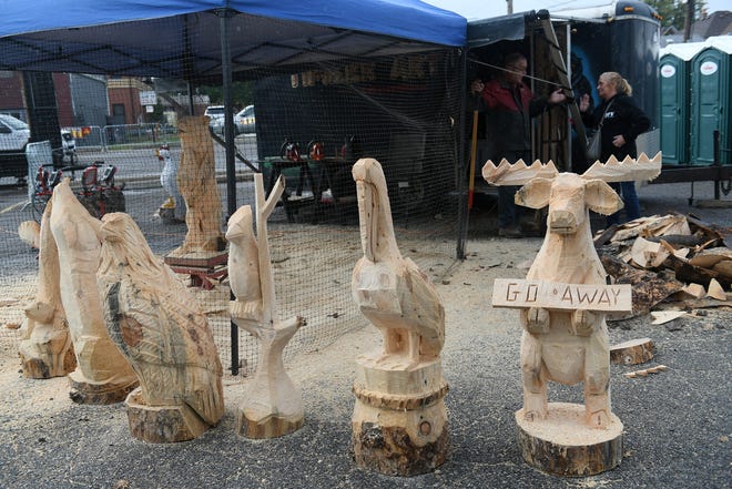 Some of the carved sculptures that Lonnie Glines of Marion has carved with his chainsaws during the Fire & Flannel Festival in Wyandotte, Mich. Photo taken on Sept. 25, 2022 while Lonnie Glines, top left, talks with Janet Straub of Southgate.