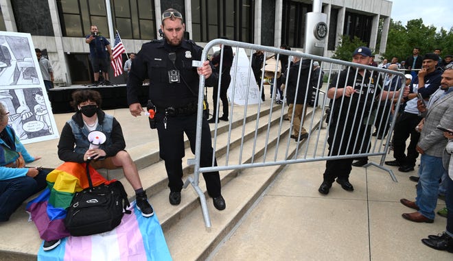 Dearborn police officers move barricades in place at the beginning of the rally to separate Rally To Protect Our Children attendees, right, from Sam Smalley, left, of Dearborn, as Smalley sits on steps in front of the podium with his transgender flag and gay pride flag, Sunday afternoon, September 25, 2022.
Approximately 800 people attend the Rally To Protect Our Children in front of the Henry Ford Centennial Library in Dearborn as they want books with sexually explicit material to be taken out of school libraries.