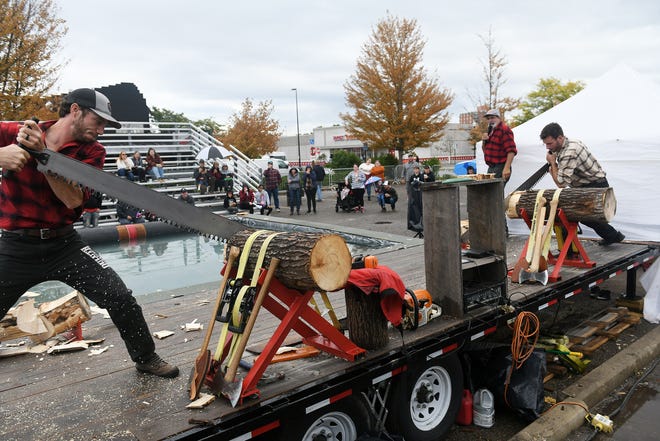 From left, Dakota Robarge, 30, and Ben Kolodziejczak, 23, of the Jack Pine Lumberjack Shows race to cut a piece off of the logs using crosscut saws at the Fire & Flannel Festival in Wyandotte, Mich. on Sept. 25, 2022.