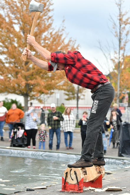 People watch as Dakota Robarge, 30, of Jack Pine Lumberjack Shows chops in two the log that his standing on racing his co-worker (out of the frame) at the Fire & Flannel Festival in Wyandotte, Mich. on Sept. 25, 2022.
