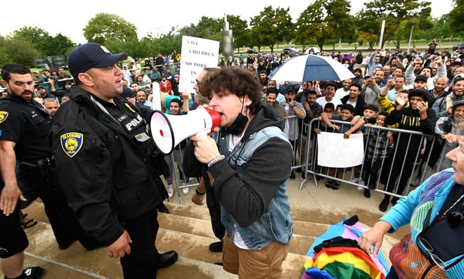 Dearborn police officers separate Rally To Protect Our Children attendees from Sam Smalley, center, of Dearborn, as Smalley yells in a bullhorn as rally speakers talk from the podium, Sunday afternoon, September 25, 2022.