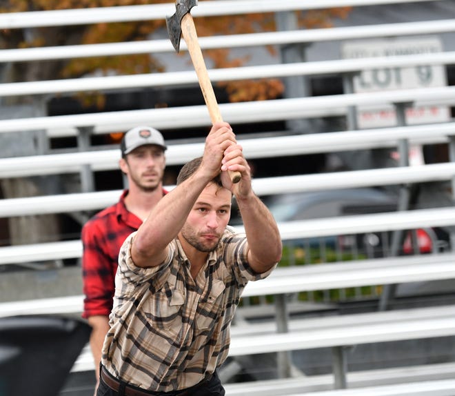 From left, Dakota Robarge, 30, watches as Ben Kolodziejczak, 23, both of the Jack Pine Lumberjack Shows is about to throw an axe at a target at the Fire & Flannel Festival in Wyandotte, Mich. on Sept. 25, 2022.