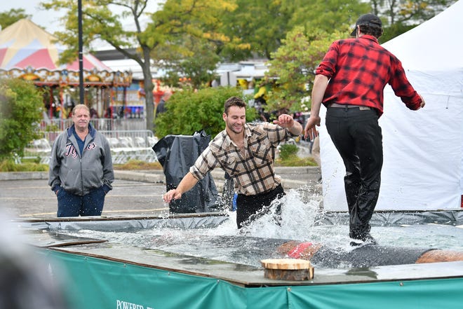 From left, Ben Kolodziejczak, 23, goes into the water while log rolling with Dakota Robarge, 30, of the Jack Pine Lumberjack Shows at the Fire & Flannel Festival in Wyandotte, Mich. on Sept. 25, 2022.
