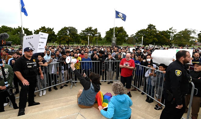 Dearborn police officers separate Rally To Protect Our Children attendees from Sam Smalley, center-left, of Dearborn, as Smalley blows a bullhorn as rally speakers talk while sitting on steps in front of the podium with his transgender flag and gay pride flag, Sunday afternoon, September 25, 2022.