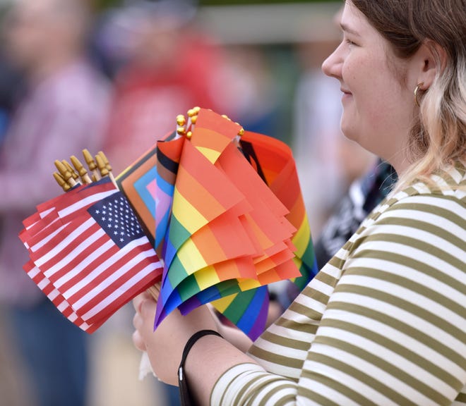 Olivia Kirk, of Dearborn, claps while holding U.S. and LGBTQIA+ flags, Sunday afternoon, September 25, 2022.