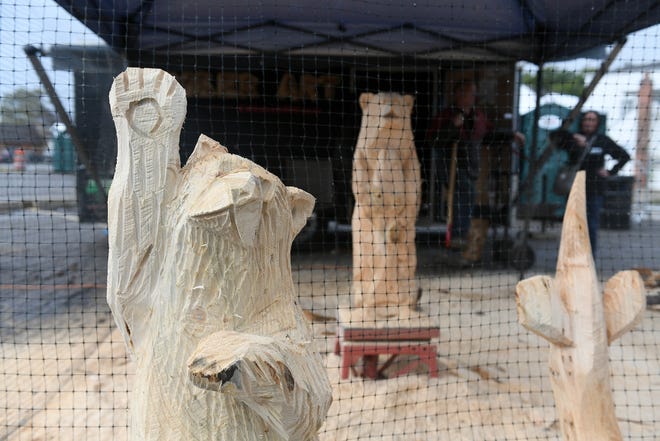 Some of the carved sculptures that Lonnie Glines of Marion has carved with his chainsaws during the Fire & Flannel Festival in Wyandotte, Mich. Photo taken on Sept. 25, 2022 while Lonnie Glines, top left, talks with Janet Straub of Southgate.