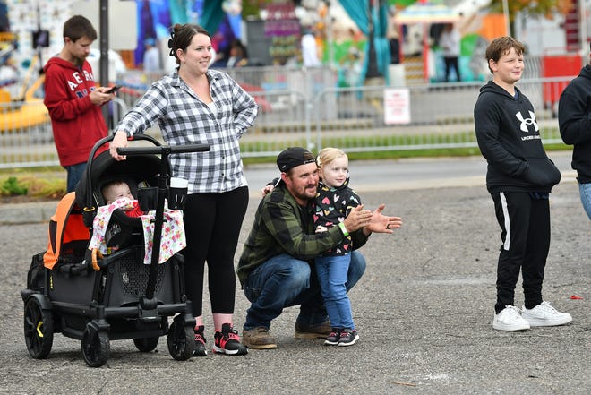 From left, The Vader family from Trenton JoJo (in stroller), Chelsey, Andy and Lily, 4, watch the Jack Pine Lumberjack Show at the Fire & Flannel Festival in Wyandotte, Mich. on Sept. 25, 2022.