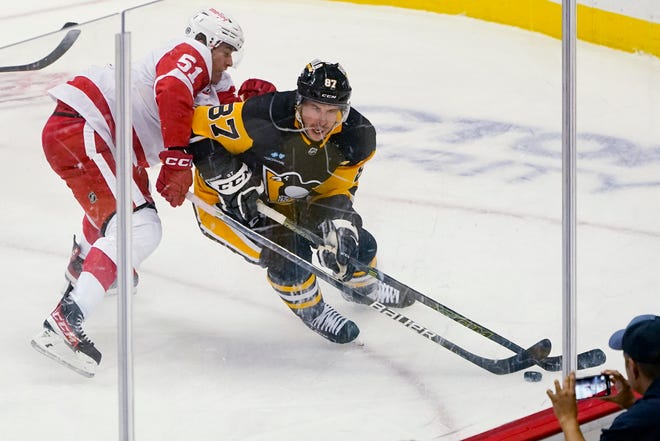 Penguins' Sidney Crosby (87) controls the puck as Red Wings' Eemil Viro defends during the first period.