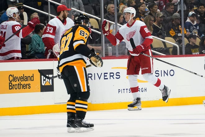 Penguins' Sidney Crosby (87) skates past as Red Wings' Elmer Soderblom is congratulated for a goal during the second period.