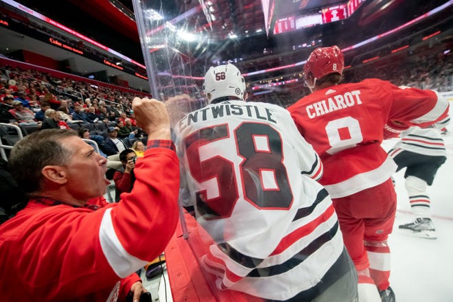 A fan slams on the glass as Detroit defenseman Ben Chiarot checks Chicago right wing MacKenzie Entwistle into the boards during the second period.