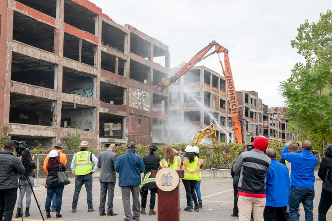 A crowd watches as demolition equipment begins work on tearing down one building of the former Packard plant, in Detroit, September 29, 2022.